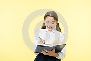 Making notes. Child school uniform kid doing homework. Child girl school uniform clothes hold book and pen. Girl cute