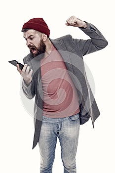 Making offensive blog comments. Angry hipster shaking fist at blog response in mobile device. Bearded man taking hard