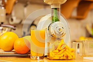 Making orange juice in juicer machine in kitchen