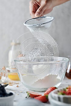 Making pancakes, cake, baking of baker hands sifting flour in bowl. Concept of Cooking ingredients and method on white marble