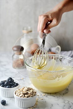 Making pancakes, cake, baking side view of baker hands pouring batter and whisking batter in bowl. Concept of Cooking ingredients