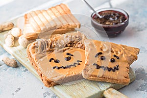 Making peanut butter sandwiches with personality! Fun smiley face drawn on with jam. Creamy peanut butter with jam on whole grain