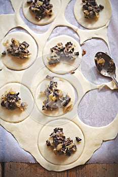 Making `Pierogi` - traditional, christmas Polish dumplings stuffed with mushrooms and sour cabbage filling. Rolled butter dough wi