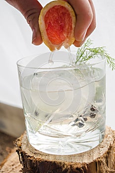 Making a Pink grapefruit and rosemary gin cocktail served in prepared glass on a tropical beach bar. Drink concept