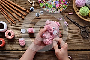 Making pink pig. Crochet toy for child. On table threads, needles, hook, cotton yarn. Step 2 - to sew all details of toy. Handmade