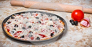Making a pizza at home with tomato, olives, ham and cheese, Cook at home concept