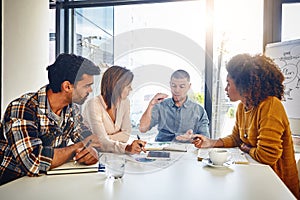 Making plans to propel their business ahead. a team of designers having a meeting in an office.