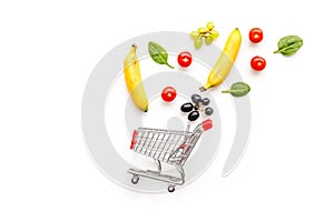 Making purchase online with mini trolley and products on white desk background top view mock up