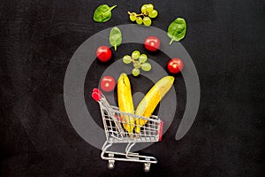Making purchase products online with fruits and mini trolley on office desk background top view mock up