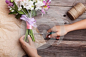 Making a rustic bouquet from gillyflowers and alstroemeria on old wooden background with wooden heart and scissors with paper