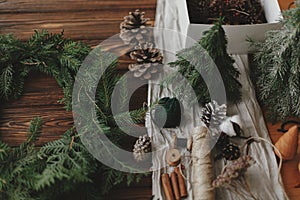 Making rustic christmas wreath on wooden table. Christmas wreath, green branches, pine cones, twine