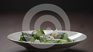 making salad shrimps fall over romaine leaves in white bowl
