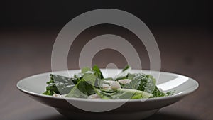 making salad shrimps fall over romaine leaves in white bowl