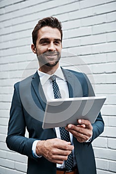 Making smart moves in a modern business world. a handsome young businessman using a digital tablet outdoors.