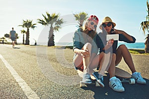 Making some summer memories. two friends hanging out on the boardwalk with a skateboard.