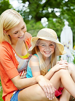 Making summer memories. Cute litte girl sitting on the grass outdoors with her mom.