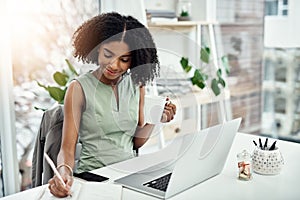 Making sure she doesnt forget. an attractive young businesswoman writing in her diary while working in the office.