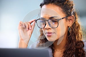 Making sure she doesnt miss a detail. an attractive young businesswoman working on her laptop in the office.