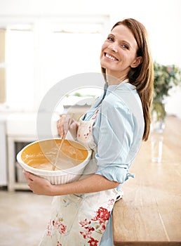 Making sure her cake mix is smooth. A mature woman happily baking in the kitchen.