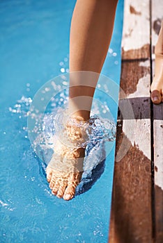 Making sure that I dont become an ice-cube. Shot of a woman testing the temperature of the pools water using her foot.