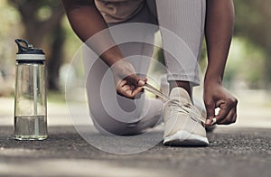 Making sure I dont trip while running. a woman tying her shoes before working out.