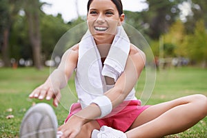 Making sure she isnt stiff the next morning. A beautiful young woman sitting in a park stretching before a jog.