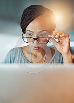 Making sure its perfect. a young woman using her laptop while working late in her office.