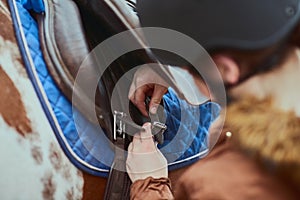 Making sure its safe and secure. a girl preparing to ride her pony on a farm.