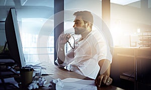 Making sure nothing is amiss. a handsome young businessman looking thoughtful while working late in the office.