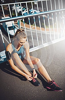 Making sure shes ready for her run. a sporty young woman tying her laces before a run.
