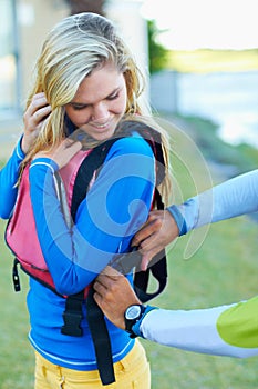 Making sure shes safe. an attractive young woman getting some assistance with her life jacket.