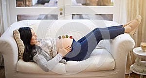 Making sure this is a stressless pregnancy. an attractive young pregnant woman balancing wooden blocks on her tummy photo