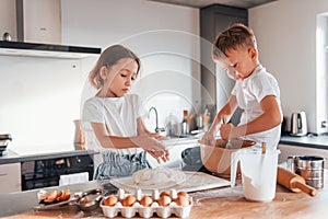 Making sweets. Little boy and girl preparing Christmas cookies on the kitchen