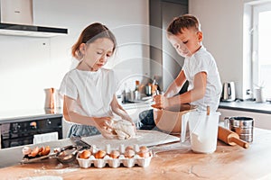 Making sweets. Little boy and girl preparing Christmas cookies on the kitchen