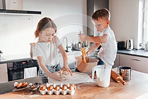 Making sweets. Little boy and girl preparing Christmas cookies on the kitchen