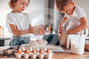 Making sweets. Little boy and girl preparing Christmas cookies on the kitchen