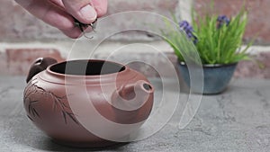 Making tea. Tea is poured into a clay teapot located on a gray stone table. Brick vintage background. Close-up, tea ceremony, mini