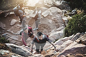 Making their way to the top. Shot of a group of friends climbing a ladder while hiking in the mountains.