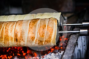 Making of traditional Kurtos Kalacs over burning charcoal photo