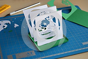 Making tunnelbook. 3D greeting card Spring. Artwork equipment and tools for paper cut - cutting knife, sharp box cutter, blue