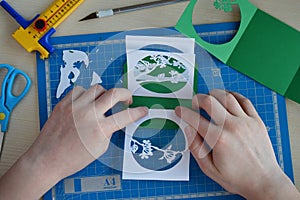 Making tunnelbook. 3D greeting card `Spring`. Artwork equipment and tools for paper cut - cutting knife, sharp box cutter, blue c