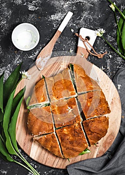 Making vegetarian sandwiches with  flatbread, cheese dip and and fresh wild garlic leaves filling for healthy snack.