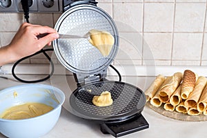 Making waffles at home - waffle iron, batter in bowl and ingredients - milk, eggs and flour. Cooking background.