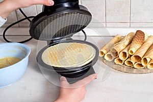 Making waffles at home - waffle iron, batter in bowl and ingredients - milk, eggs and flour. Cooking background.