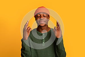 Making Wish. Portrait Of Young Black Guy Keeping His Fingers Crossed