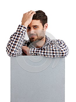 Making your copyspace look good. Studio portrait of a handsome young man leaning on a blank placard isolated on white.