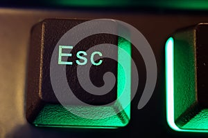 Makro closeup of isolated green illuminated esc key on computer keyboard