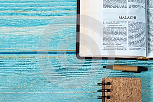 Malachi open Holy Bible Book on a rustic wooden table background