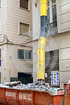 Loaded dumpster near a building in renovation