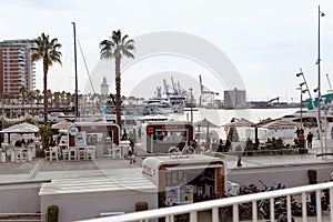 Malaga, Spain- 26-01-2024: Vibrant scene at Puerto de Malaga with outdoor cafes, palm trees, and yachts, a perfect